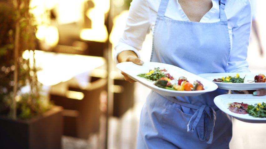 Waitress delivers food at work in the restaurant